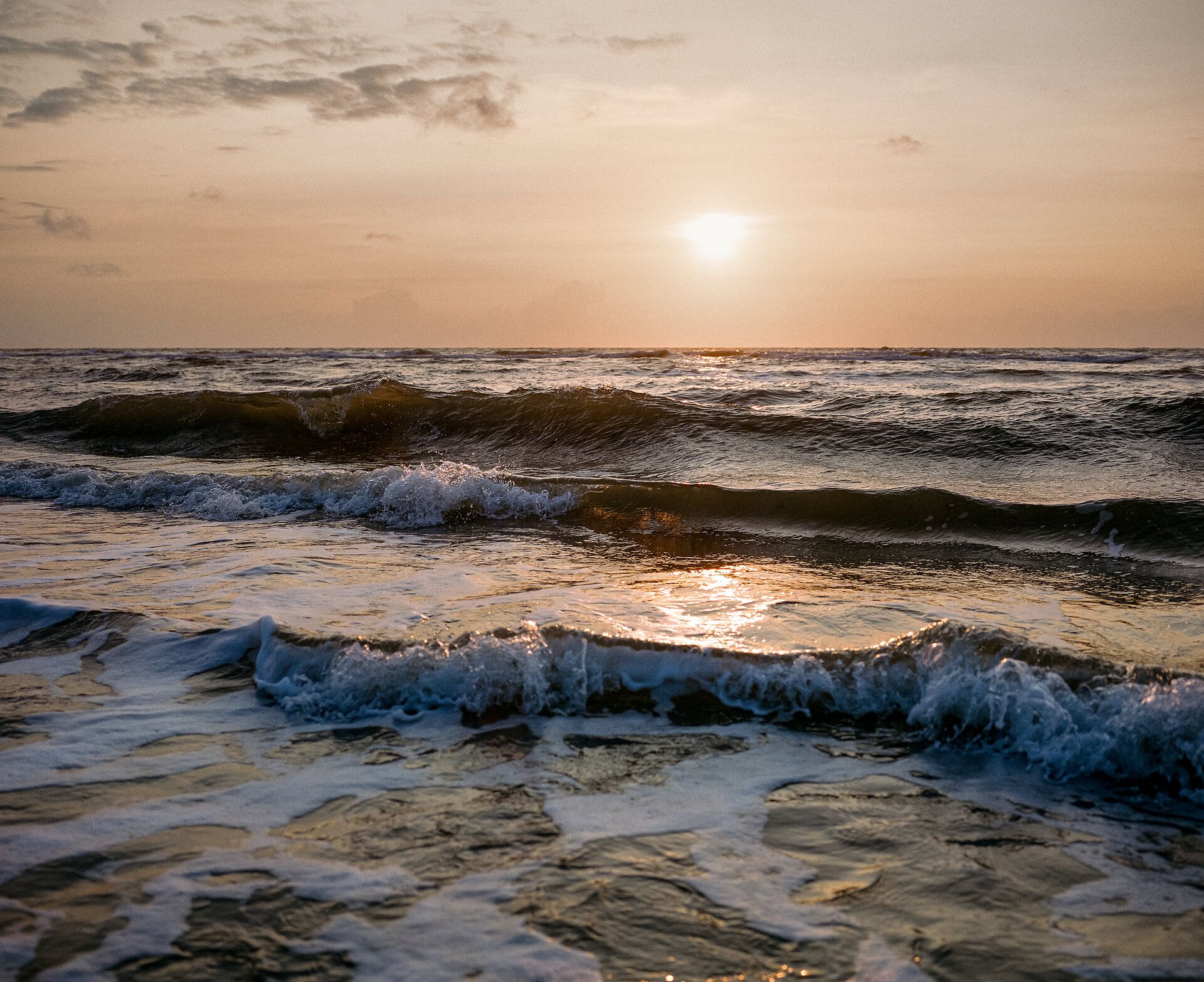 Sonnenuntergang über leichten Wellen am Amrumer Kniepsandstrand