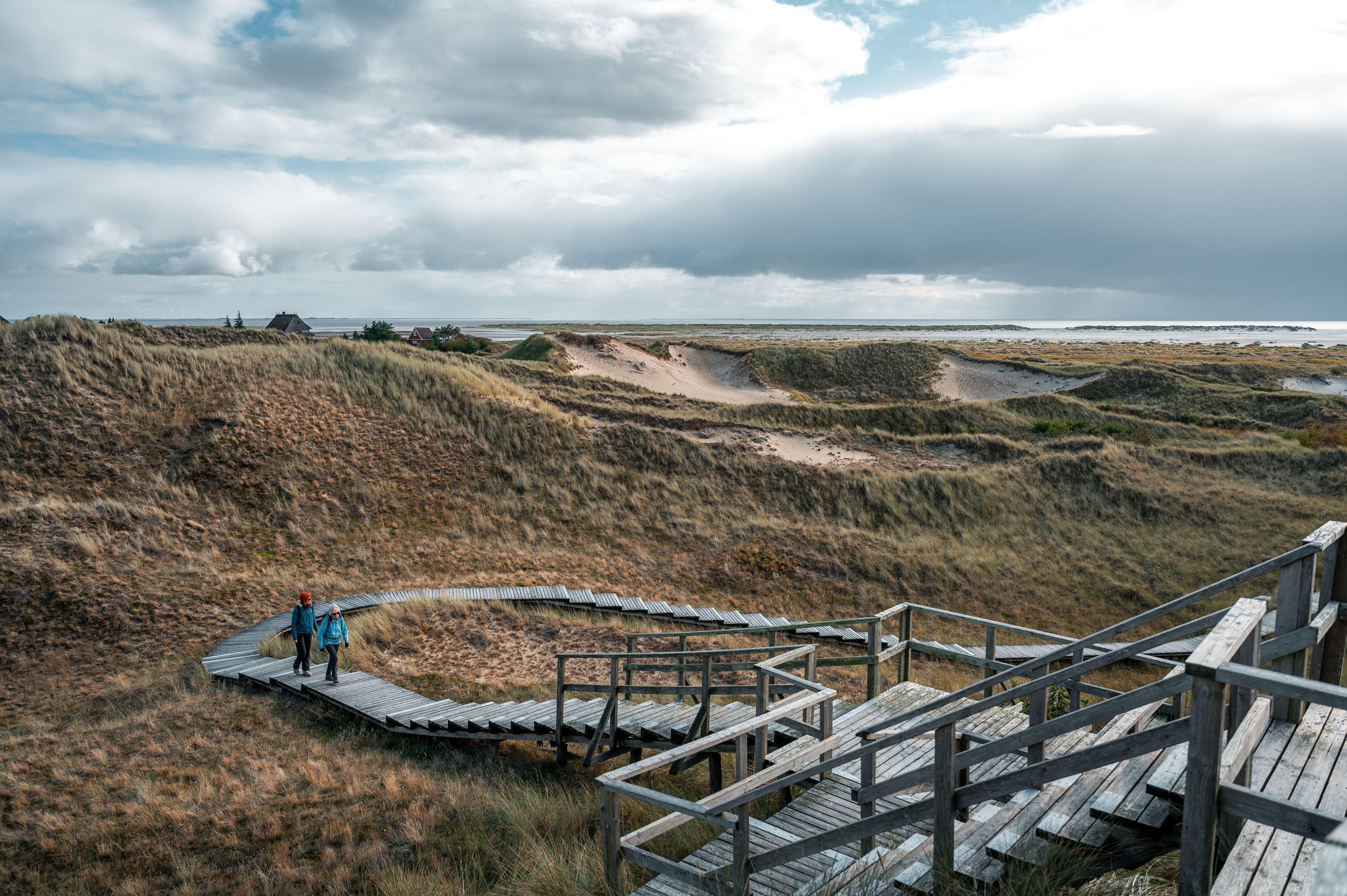 Blick von der Aussichtsdüne in Wittdün auf Amrum im Winter. Die Dünen sind friedlich und verlassen nur zwei Personen laufen über den darüber führenden Bohlenweg.