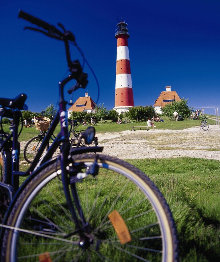 Ein Fahrrad steht im Vordergrund, im Hintergrund ist der Westerhever Leuchtturm zu sehen