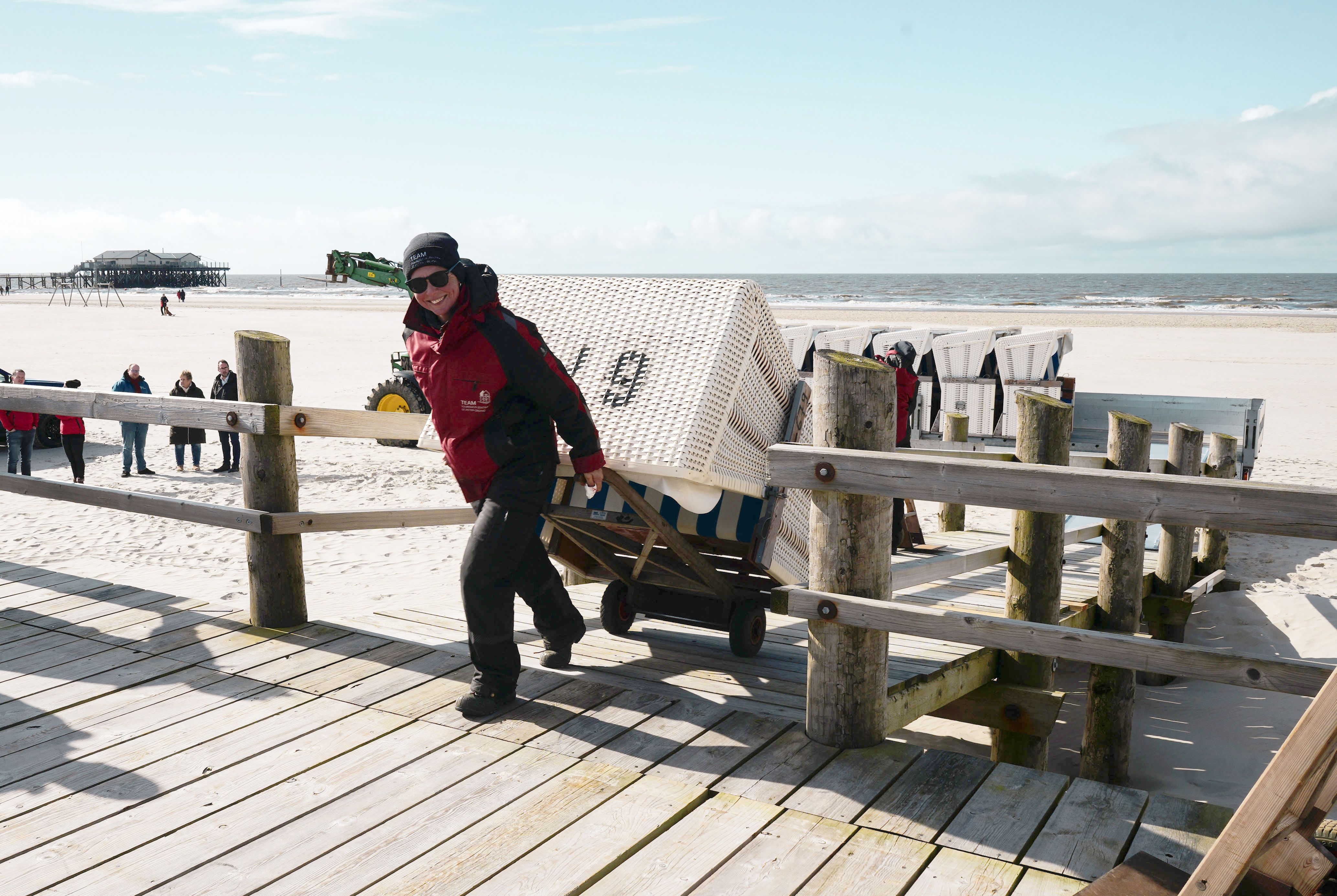 Eine Mitarbeiterin der Tourismuszentrale in SPO zieht einen Strandkorb auf einer Strandkorb-(Sack-)Karre, die Rampe eines Abstellpodestes hoch. – Foto: TZ SPO